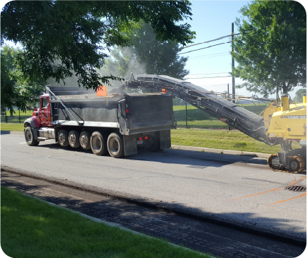 Commercial asphalt milling equipment loading old pavement into dump truck for restoration project in Delaware, Ohio.
